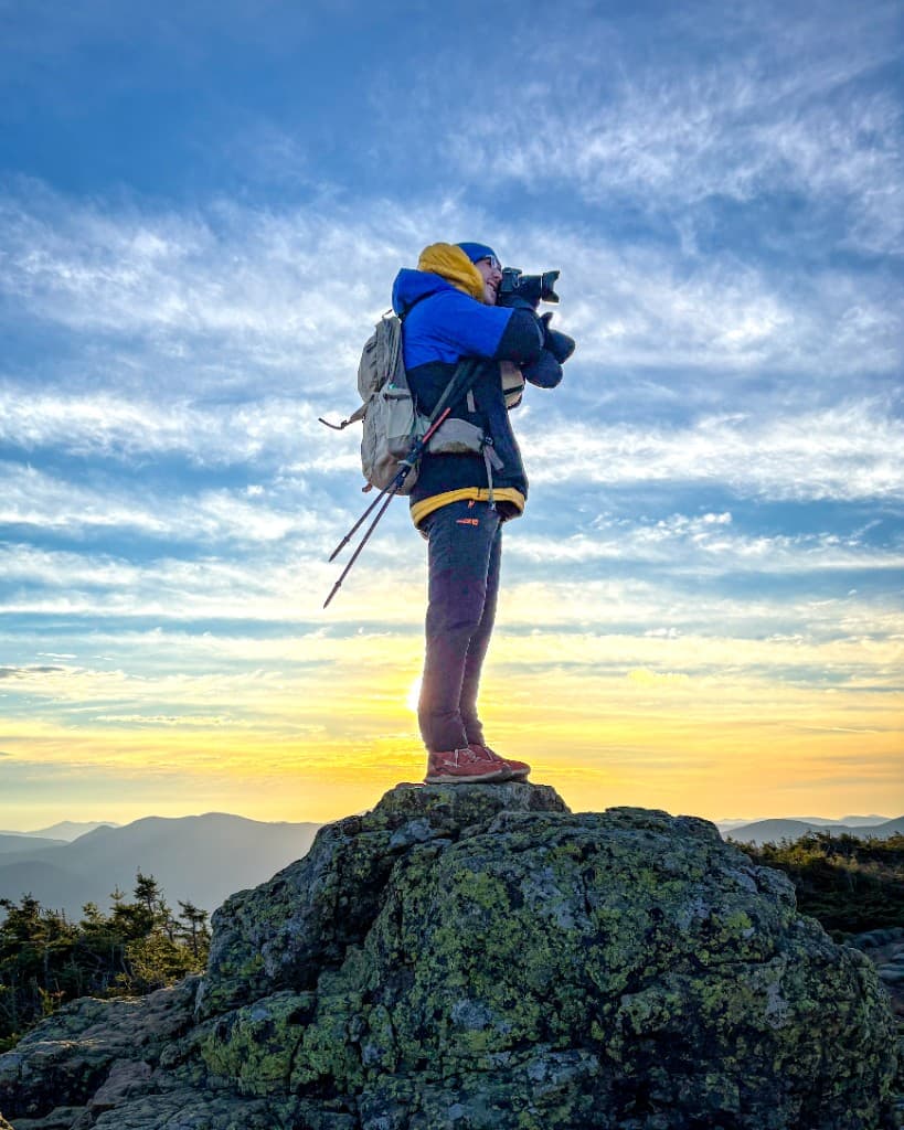 Zach Comeau photographing a sunrise from a mountain summit